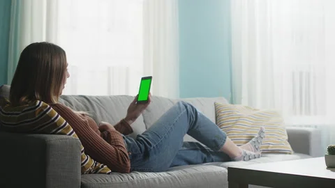 Young lady is lying on a beige sofa and talking on a video call. Chromakey Stock Footage 146704387
