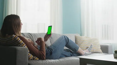 Young lady is lying on a beige sofa and talking on a video call. Chromakey Stock Footage 146754252