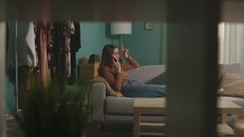 Young lady is lying on couch and anxiously talking on phone Stock Footage 139924150