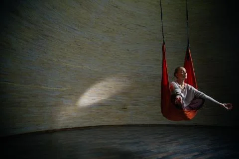Young lady meditating in hammock while doing aerial yoga Stock Photos