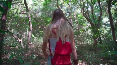 A young lady moves slowly through the forest, enjoying the surrounding nature. Video stock 268785059