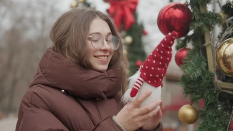 Young lady observes Christmas decorations happily. Young woman with bright smile Stock Footage 345553470