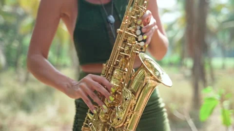 A young lady performs in a long green dress, playing the golden saxophone. Video stock 234022517