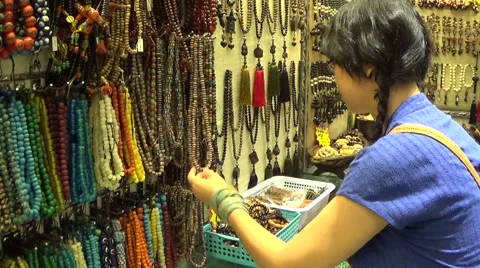 Young lady picking and choosing handmade prayer beads necklaces in the store Stock Footage 42599423