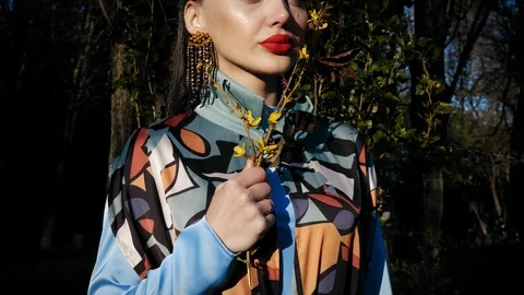 Young lady with plump red lips in earrings holds spring twig Stock Footage 108260901