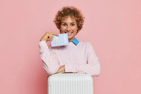 Young lady posing on pink background with white suitcase, dressed in sweatshirt Stock Photos