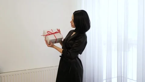 Young lady with a present box. Beautiful brunnete girl holding a gift. A woman Stock Footage 149066635