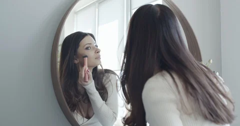 The young lady puts on make-up in the mirror in the bedroom Stock Footage 127849766
