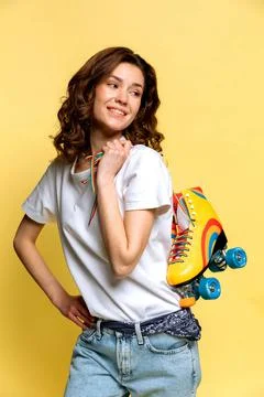 A young lady with rainbow quad rollers on yellow background Stock Photos