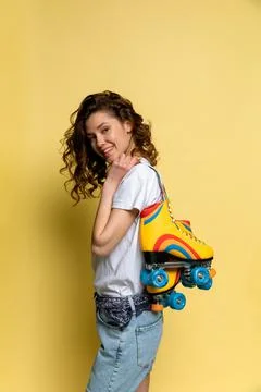 A young lady with rainbow quad rollers on yellow background Stock Photos