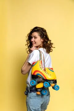 A young lady with rainbow quad rollers on yellow background Stock Photos