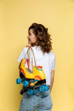 A young lady with rainbow quad rollers on yellow background Stock Photos