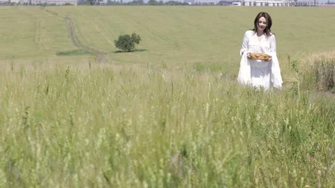 Young lady with round bread in wheat field. Stock Footage