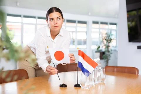 Young lady sets miniatures flags of Netherlands and Japan for international Stock Photos