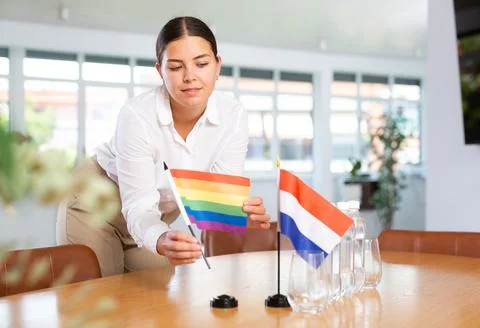 Young lady sets miniatures flags of Netherlands and LGBT for international Stock Photos