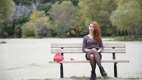 Young lady sitting on bench, cover her body with a umbrella Stock Footage 69865211