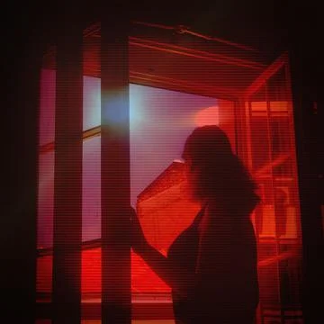 Young lady standing next to window and looking at sun corona and its dazzling li Stock Photos