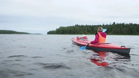 Young lady in sunglasses rows bright orange sports kayak with little kid sailing Stock Footage 152173596