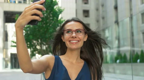 Young lady taking selfies in front of a business center Stock Footage 68597959