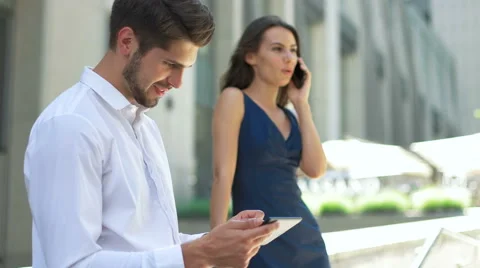 Young lady talking on her phone , while her colleague use his tablet Stock Footage 68598591