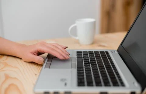 Young lady using a gray laptop computer and black keyboard with a hand on the 写真素材