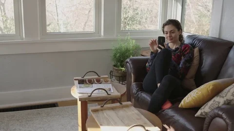 Young lady using her cell phone in sunroom Stock Footage 70808932