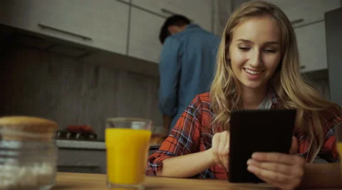 Young lady using tablet, while man preparing food Stock Footage 68731946