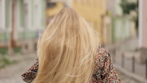 Young lady is walking down a city street, turns around and looks at the camera Stock Footage 236558924