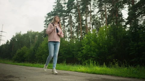 Young Lady Walking Thoughtfully Along Tarred Road Holding Bag Strap Stock Footage 310210835