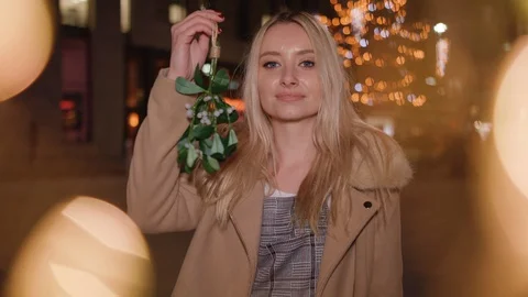 Young lady waves mistletoe in the air and smiles at you - in slow motion Stock Footage
