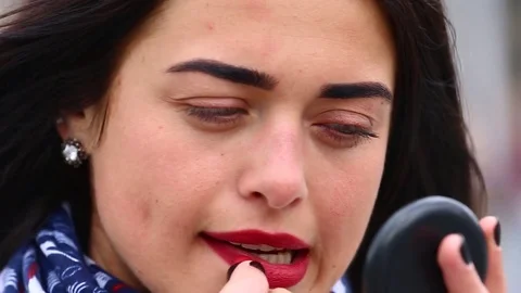 Young lady while looking on the mirror make her lips red lipstick on the street. Stock Footage 75582583