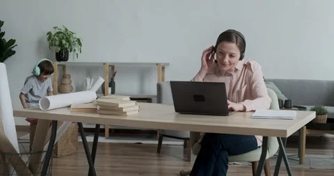 Young lady working remotely from home on video conference when son rushes up and Stock Footage 165774741