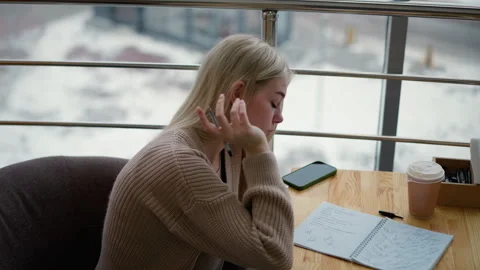 Young lady writes thoughtfully with coffee and phone on table, winter background Video stock 303069611