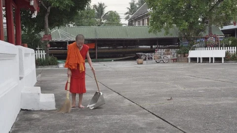 Young laotian buddhist monk sweeping and clean the street inside the temple Stock Footage 111351853