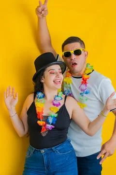 Young latin couple, dancing while laughing loudly, he's behind her. yellow .. Foto stock