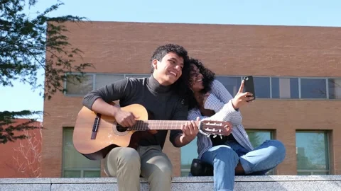 Young latin couple playing the guitar and recording them with the smartphone Stock Footage