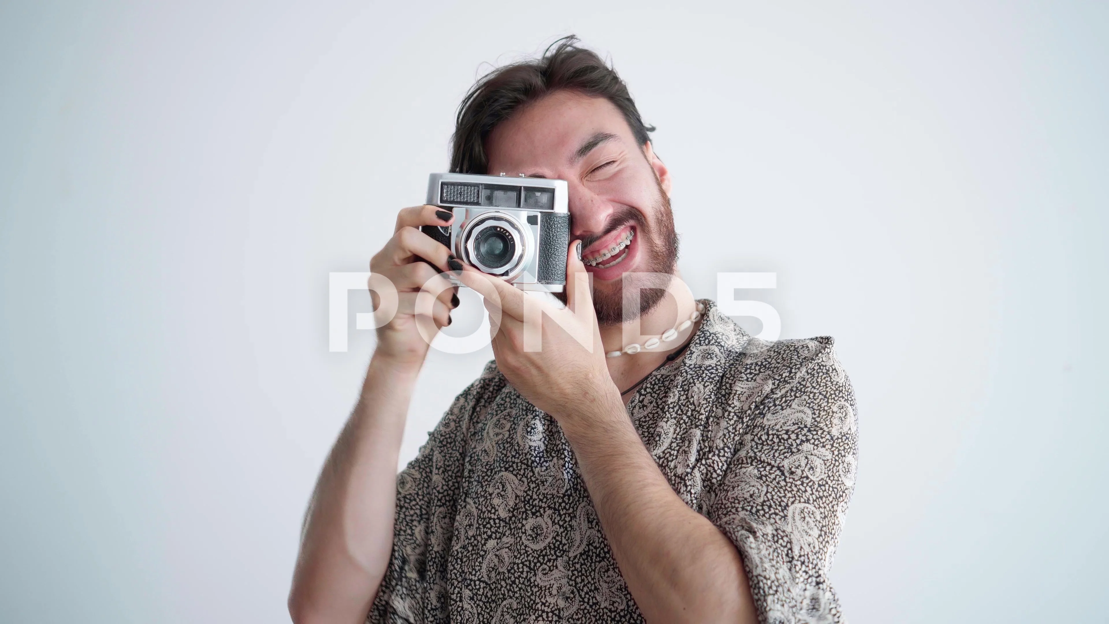 Young latin gay queer man taking a picture with an old analog camera and  th..