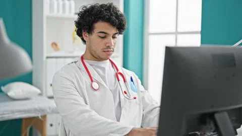 Young latin man doctor using computer working at clinic Video stock 247377140