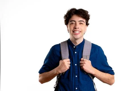 Young latin man grins at camera with backpack, at blank background Stock Photos
