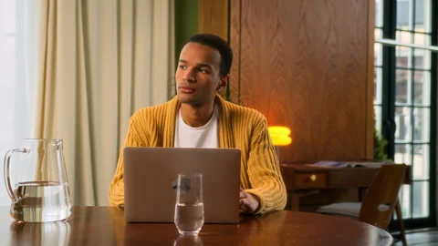 Young Latin man sits at table working at laptop at home Stock Footage 267676179