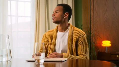 Young Latin man sits at table working at laptop at home Stock Footage 267676719