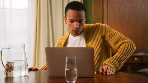 Young Latin man sits at table working at laptop at home Stock Footage 267677071