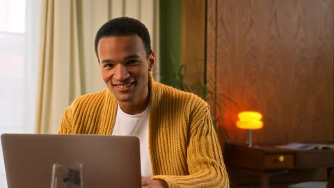 Young Latin man sits at table working at laptop at home Stock Footage 267677352