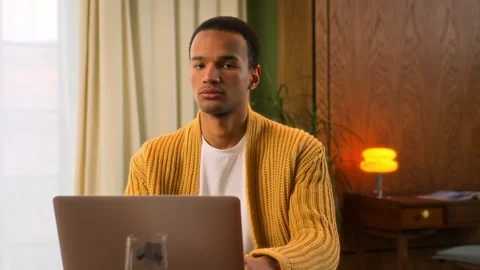 Young Latin man sits at table working at laptop at home Stock Footage 267677733
