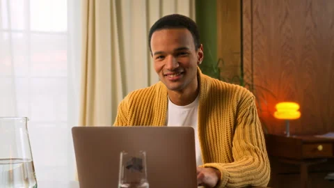 Young Latin man sits at table working at laptop at home Stock Footage 267678021