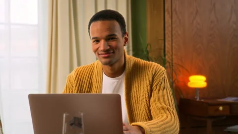 Young Latin man sits at table working at laptop at home Stock Footage 267678340