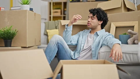 Young latin man sitting on floor stressed at new home Video stock 247377113