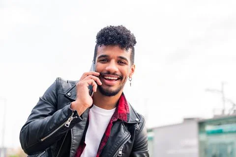Young latin man smiling while talking on the phone Stock Photos