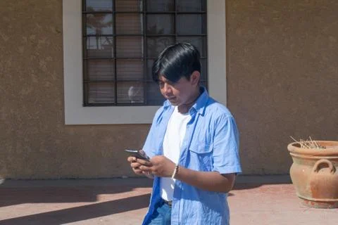 Young latin man using cell phone in the street 库存照片