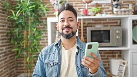 Young latin man using smartphone saying yes with head at dinning room Stock Footage 243496186